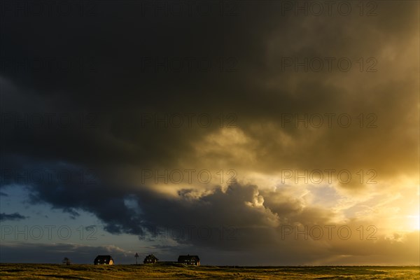 Dune landscape with storm clouds and houses