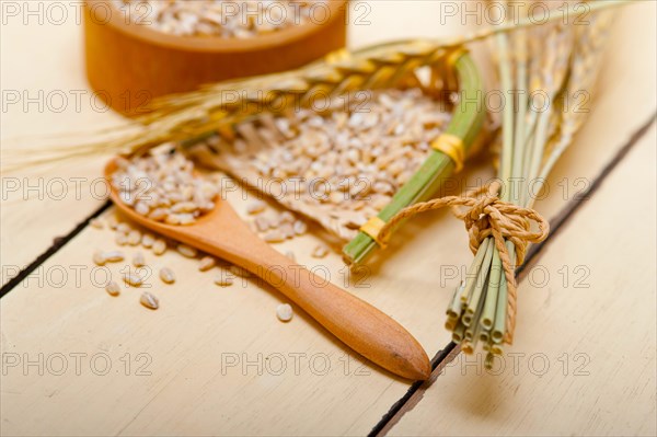 Organic barley grains over rustic wood table macro closeup