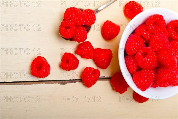 Bunch of fresh raspberry on a bowl and white wood rustic table