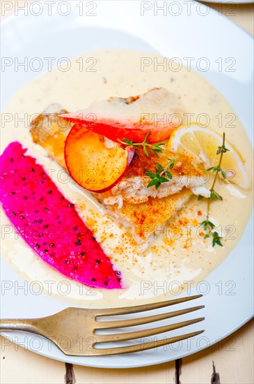 Sea bream orata fillet butter pan fried with fresh peach prune and dragonfruit slices thyme on top