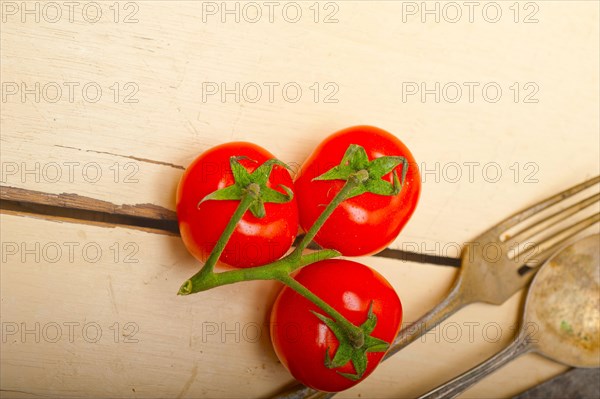 Ripe cherry tomatoes cluster over white rustic wood table