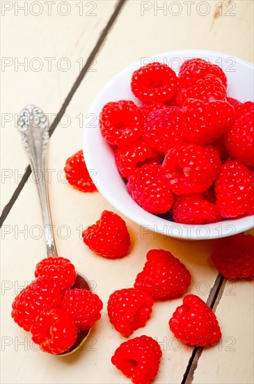 Bunch of fresh raspberry on a bowl and white wood rustic table