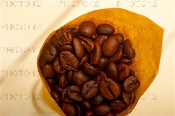 Espresso coffee beans on a paper cone cornucopia over white background