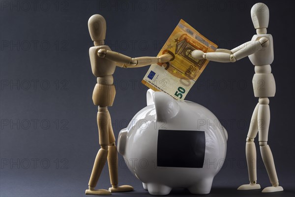 Piggy bank and mannequins throwing a banknote into it