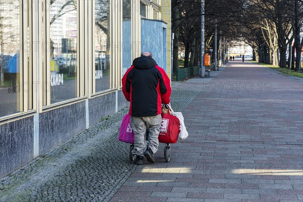 Senior citizen with walking frame and bags full of returnable bottles