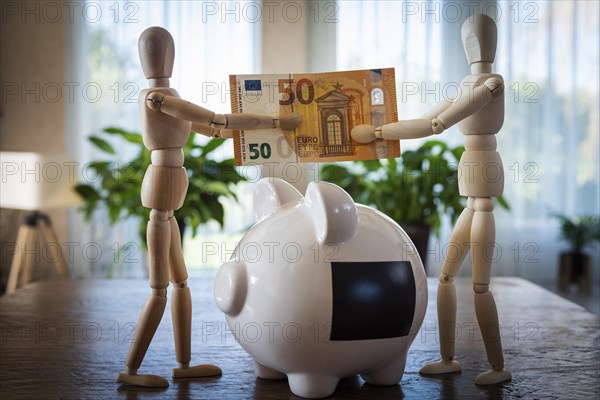 Piggy bank and mannequins throwing a banknote into it