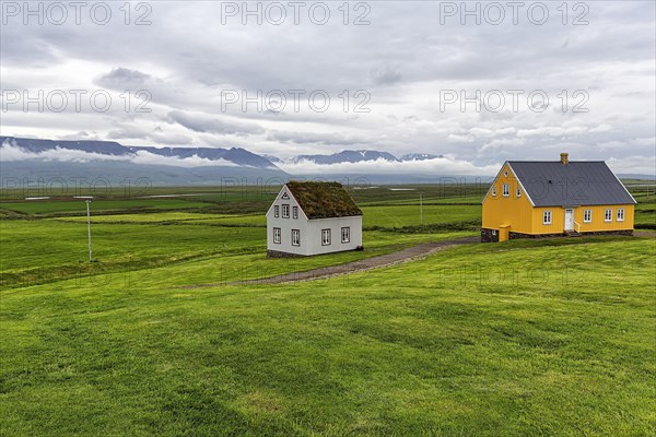 Grass sod house and yellow wooden house in a meadow
