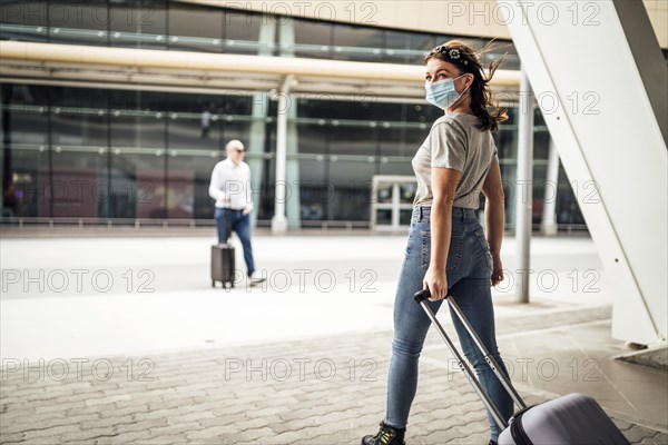 Ayoung woman wearing mask walking with the luggage to the airport