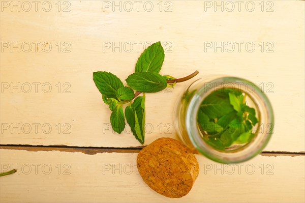 Fresh mint leaves on a glass jarover a rustic white wood table