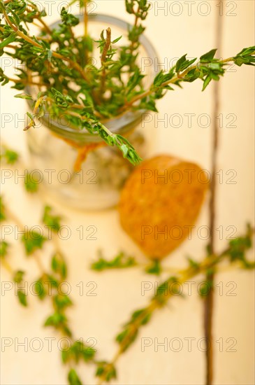 Fresh thyme on a glass jar over a white wood rustic table