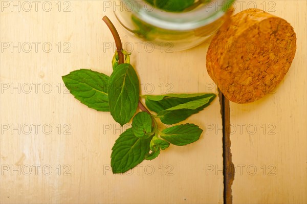 Fresh mint leaves on a glass jarover a rustic white wood table
