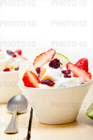 Fruit and yogurt salad healthy breakfast over white wood table