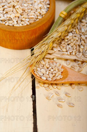 Organic barley grains over rustic wood table macro closeup