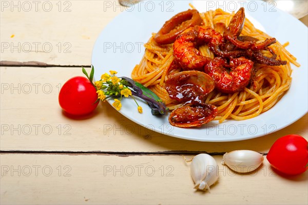 Italian seafood spaghetti pasta on red tomato sauce over white rustic wood table