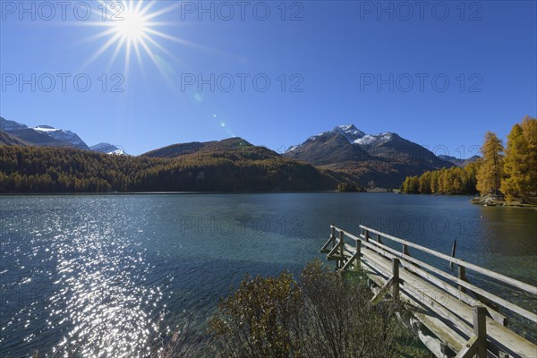 Wooden jetty on lake with sun in autumn