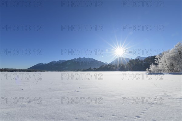 Frozen lake Barmsee with Karwendel mountainrange on morning with sun in winter