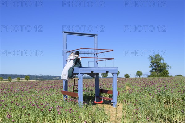 Opium poppy field with big chair and bridal couple dolls