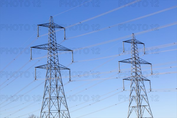 Electrical pylons and high voltage electricity transmission power lines from Sizewell nuclear power station against blue sky
