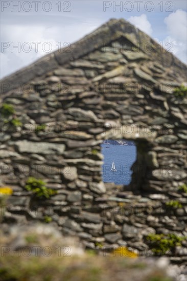 Decaying gable end and window of former village house on Great Blasket Island with view of Blasket Sound. County Kerry