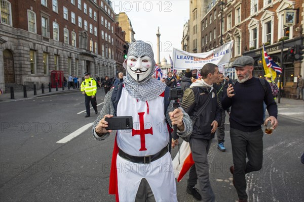 Man in St George uniform with mobile phone at a Leave means Leave march