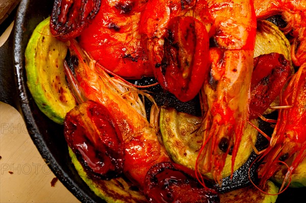 Roasted shrimps on cast iron skillet with zucchini and tomatoes