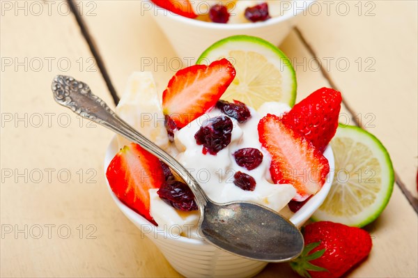 Fruit and yogurt salad healthy breakfast over white wood table