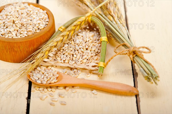 Organic wheat grains over rustic wood table macro closeup