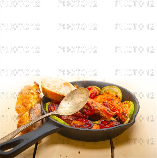 Roasted shrimps on cast iron skillet with zucchini and tomatoes