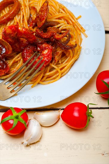 Italian seafood spaghetti pasta on red tomato sauce over white rustic wood table