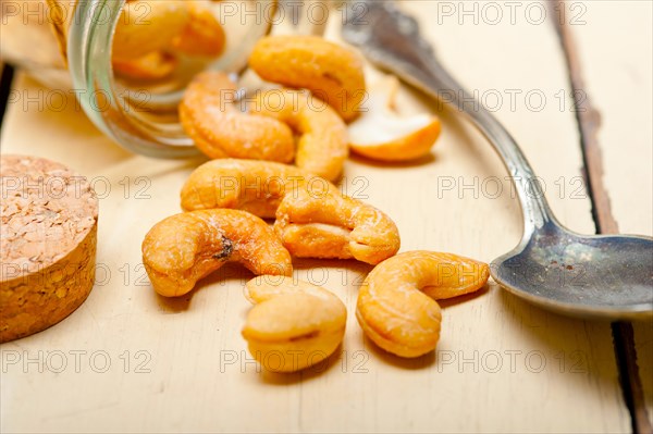 Cashew nuts on a glass jar over white rustic wood table