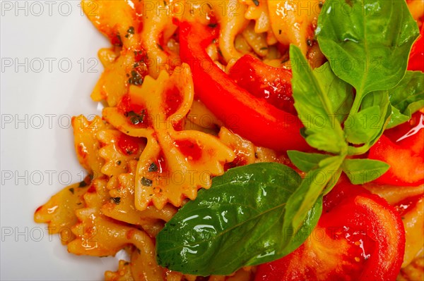 Italian pasta farfalle butterfly bow-tie with tomato basil sauce over white rustic wood table