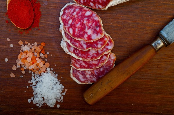 Traditional Italian salame cured sausage sliced on a wood board