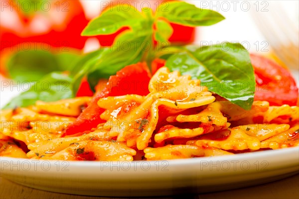 Italian pasta farfalle butterfly bow-tie with tomato basil sauce over white rustic wood table