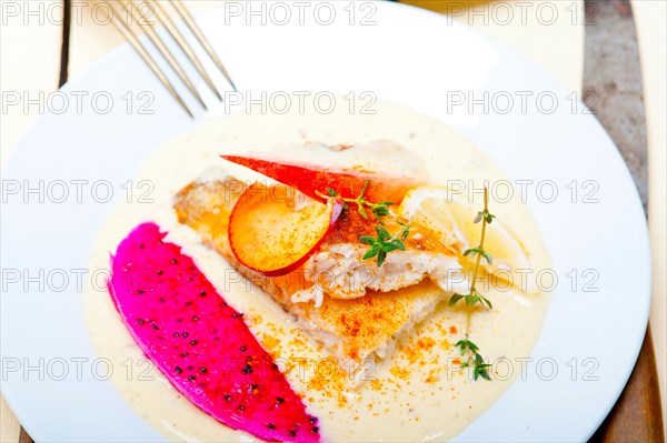 Sea bream orata fillet butter pan fried with fresh peach prune and dragonfruit slices thyme on top