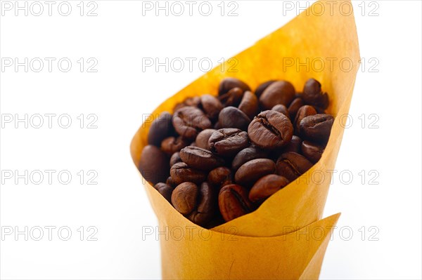 Espresso coffee beans on a paper cone cornucopia over white background