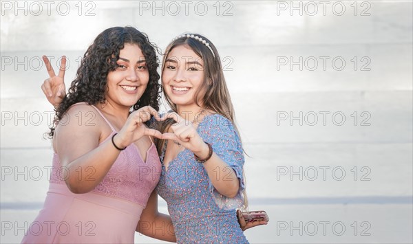 Close up of two girls forming heart with hands