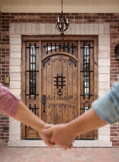 A couple holding his hands approaching the front door of a house