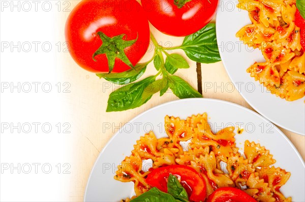 Italian pasta farfalle butterfly bow-tie with tomato basil sauce over white rustic wood table