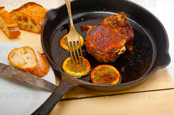 Pork chop seared on iron skillet with lemon and spices seasoning
