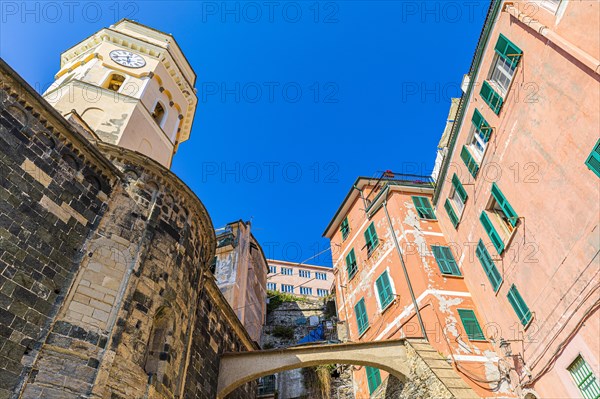 The steeple of the church of Santa Margherita di Antiochia and nested houses built into the hillside with pastel-coloured facades