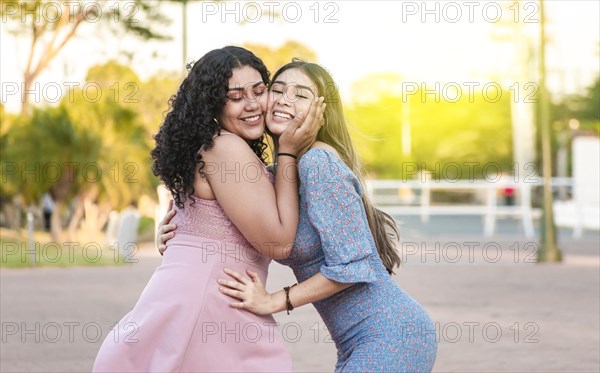 Two female friends hugging in front outdoors