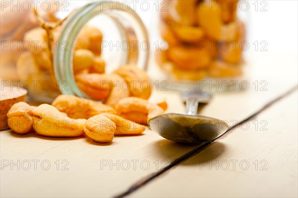 Cashew nuts on a glass jar over white rustic wood table