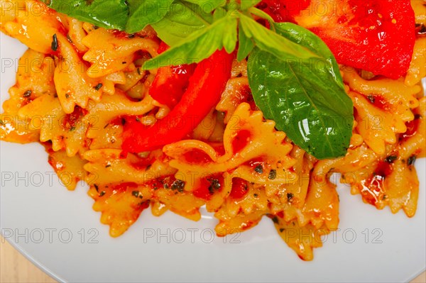 Italian pasta farfalle butterfly bow-tie with tomato basil sauce over white rustic wood table