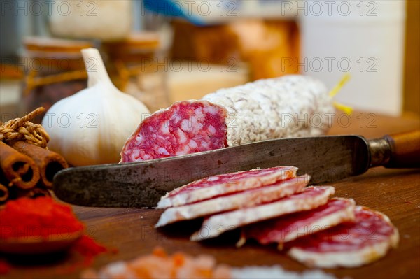 Traditional Italian salame cured sausage sliced on a wood board