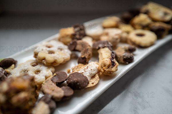 Sweet biscuits with chocolate coating lie on a rectangular white plate ready to be eaten