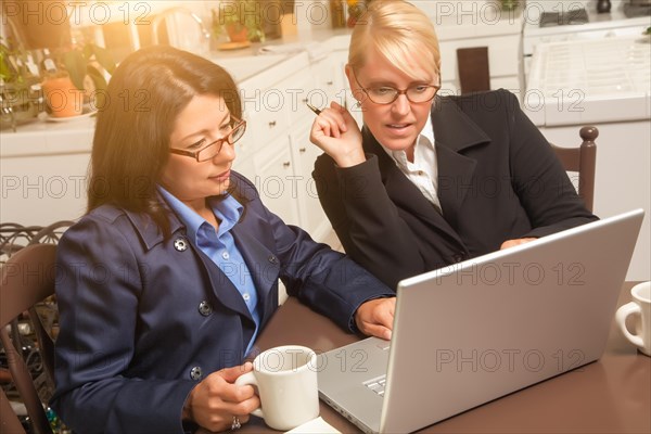 Businesswomen working on the laptop together in the kitchen