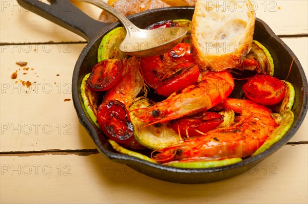 Roasted shrimps on cast iron skillet with zucchini and tomatoes