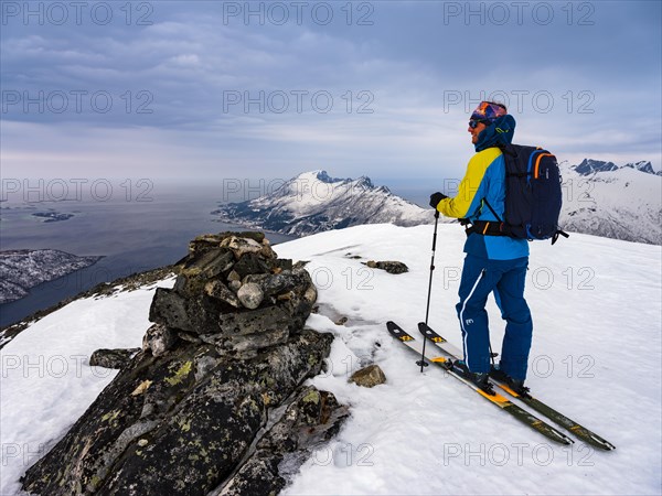 Ski mountaineers at the summit of Flobjoern with a view over the Bergsfjord