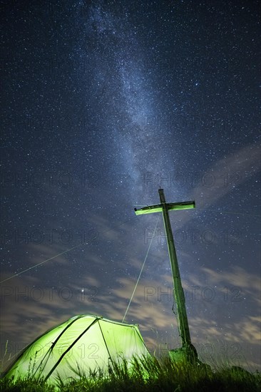 Green tent with summit cross under a starry sky on Portlakopf