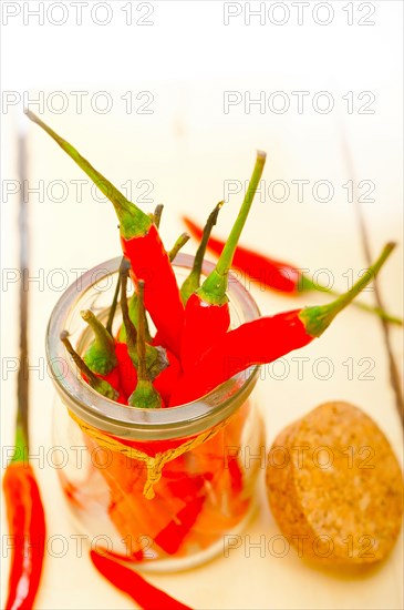 Red chili peppers on a glass jar over white wood rustic table